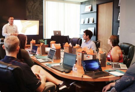 Pitch Presentation - man standing in front of people sitting beside table with laptop computers